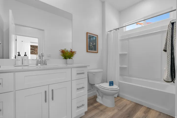 White vanity with ample storage, integrated sink, chrome faucet, and wood-finish flooring