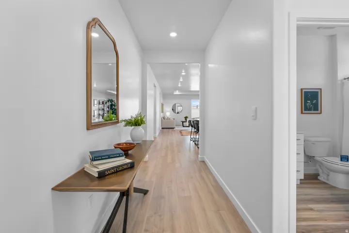 Recessed lighting illuminates the hallway, featuring wood-finish flooring and crisp white walls