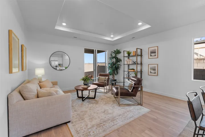 Recessed ceiling with integrated lighting, light wood-finish flooring, white walls, and a sliding glass door