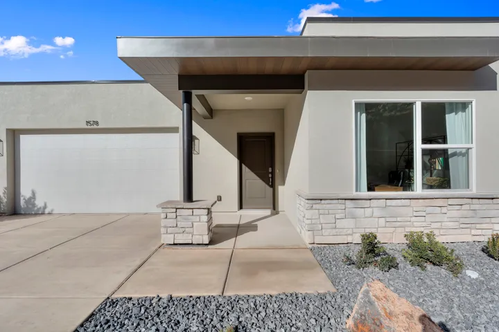 Modern facade with stucco exterior, a large single-pane window, and a stone accent wall