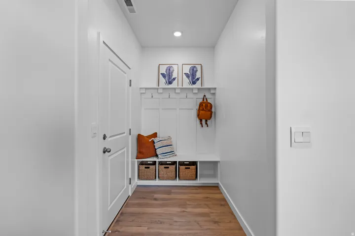 Mudroom featuring built-in bench seating, wood-finish flooring, coat hooks, overhead shelf, and recessed lighting
