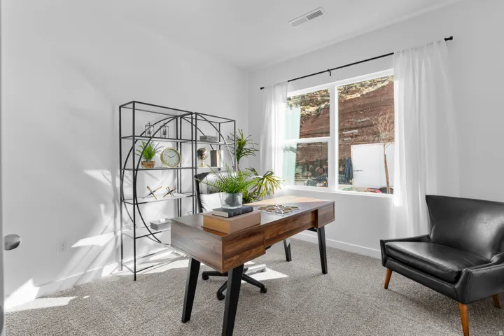 Spacious room featuring a large window, light-colored carpet, and white walls