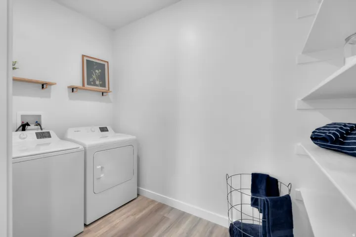 Dedicated laundry area featuring wood-finish flooring and integrated shelving