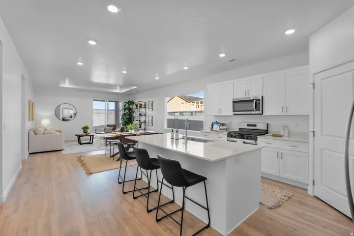 Open-concept living space featuring wood-finish flooring, recessed lighting, and a kitchen island with seating