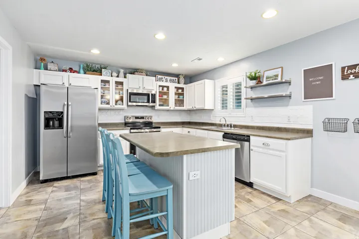 Kitchen featuring an island, white cabinetry, stainless steel appliances, and a tiled backsplash