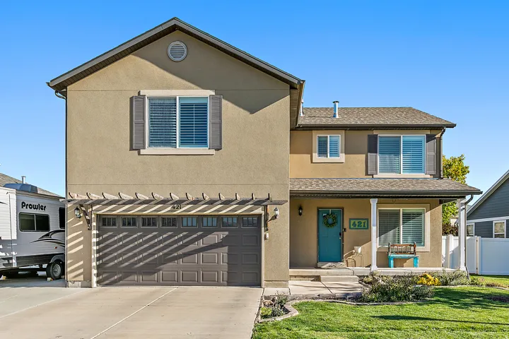 Two-story stucco exterior with a covered porch, attached two-car garage, and a pergola accent