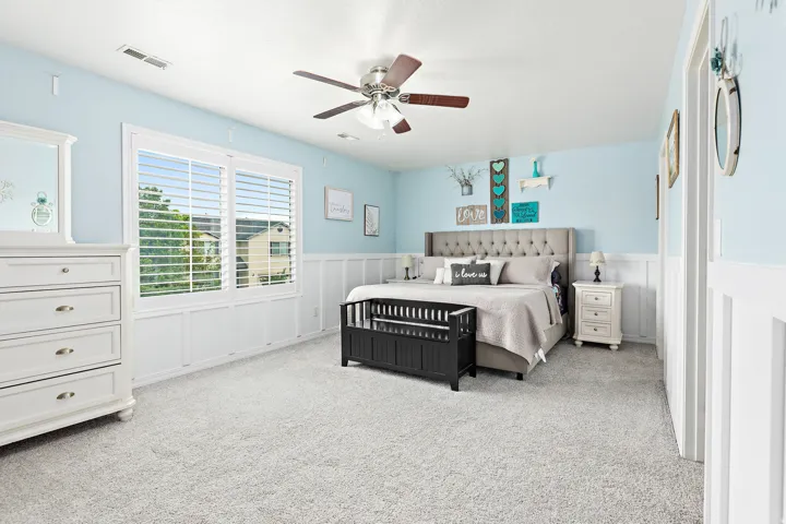 Carpeted flooring, white trim details, window with horizontal blinds, and a ceiling fan with integrated lighting