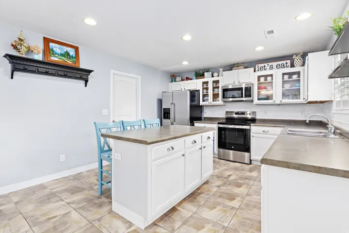 Kitchen featuring a central island with countertop, white cabinetry, stainless steel appliances, and tile flooring