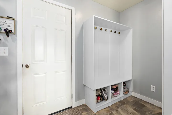 Entryway featuring a six-panel door, built-in storage unit with hooks, open shelving, and wood-finish flooring