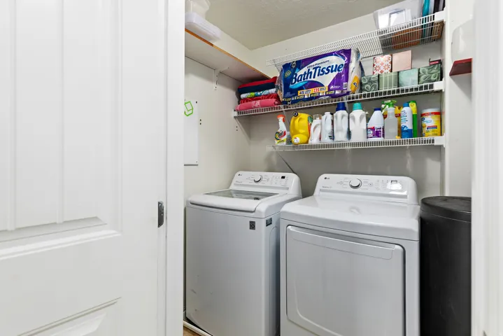 Dedicated laundry area featuring a washer and dryer, along with two tiers of wire shelving for organized storage