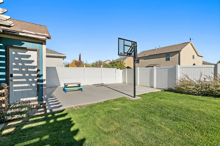 Expansive backyard featuring a green lawn, concrete patio, privacy fencing, and a detached shed