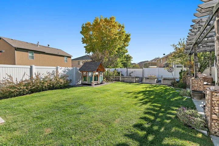 Expansive lawn area with a white privacy fence, bordered by established shrubbery