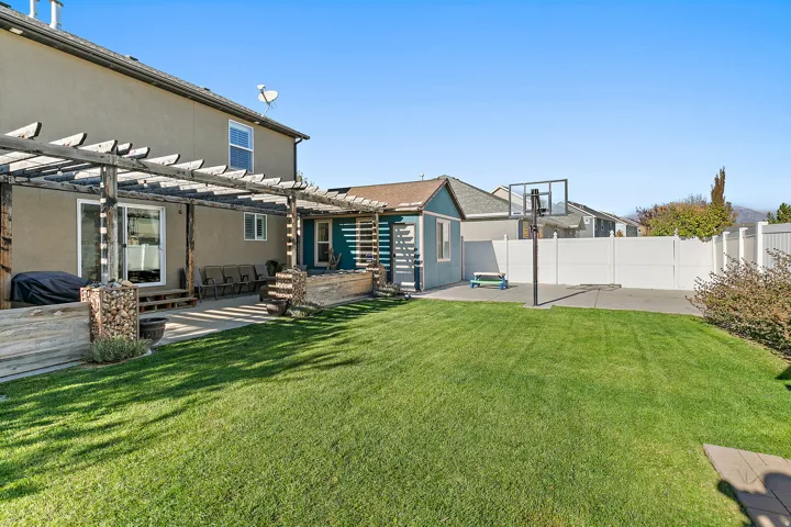 Expansive green lawn, a pergola-covered patio, built-in raised planters, a private shed, and a concrete pad