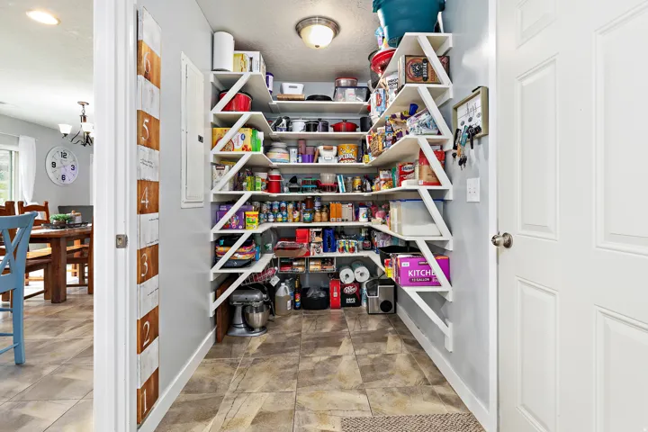 Spacious pantry featuring custom-built shelving, recessed lighting, and tile flooring