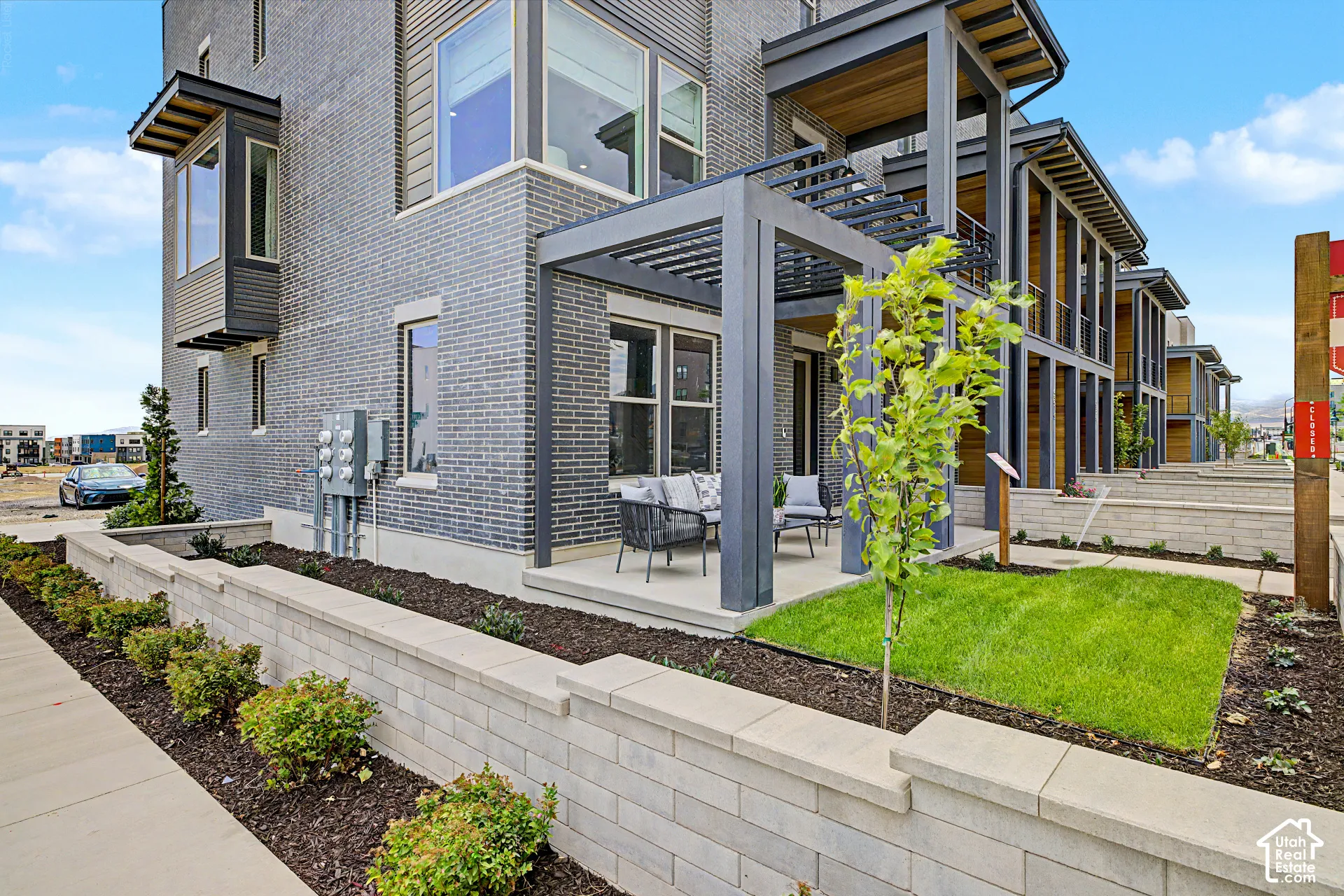 Modern exterior featuring grey brick, prominent bay windows, and a patio with a pergola