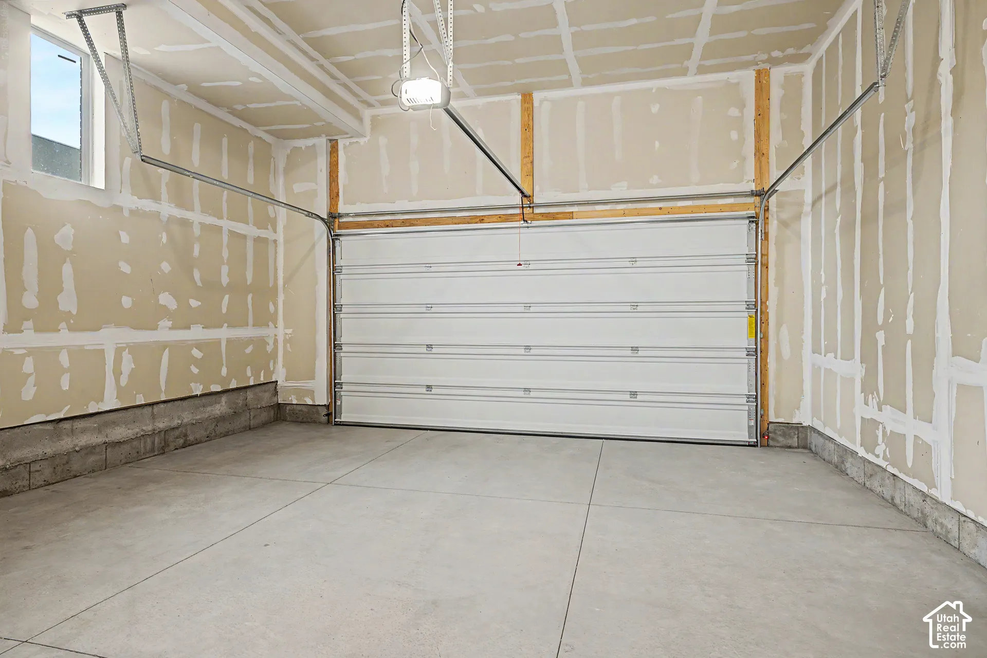 Concrete flooring with a white sectional garage door and exposed wall framing