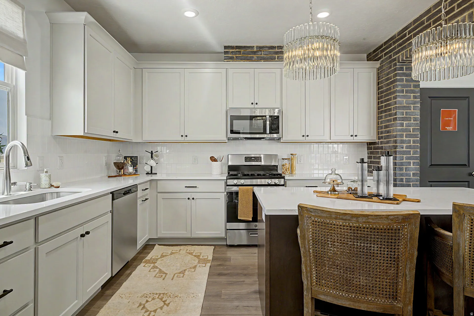 Modern kitchen featuring white shaker cabinetry, stainless steel appliances, white subway tile backsplash, and wood-finish flooring