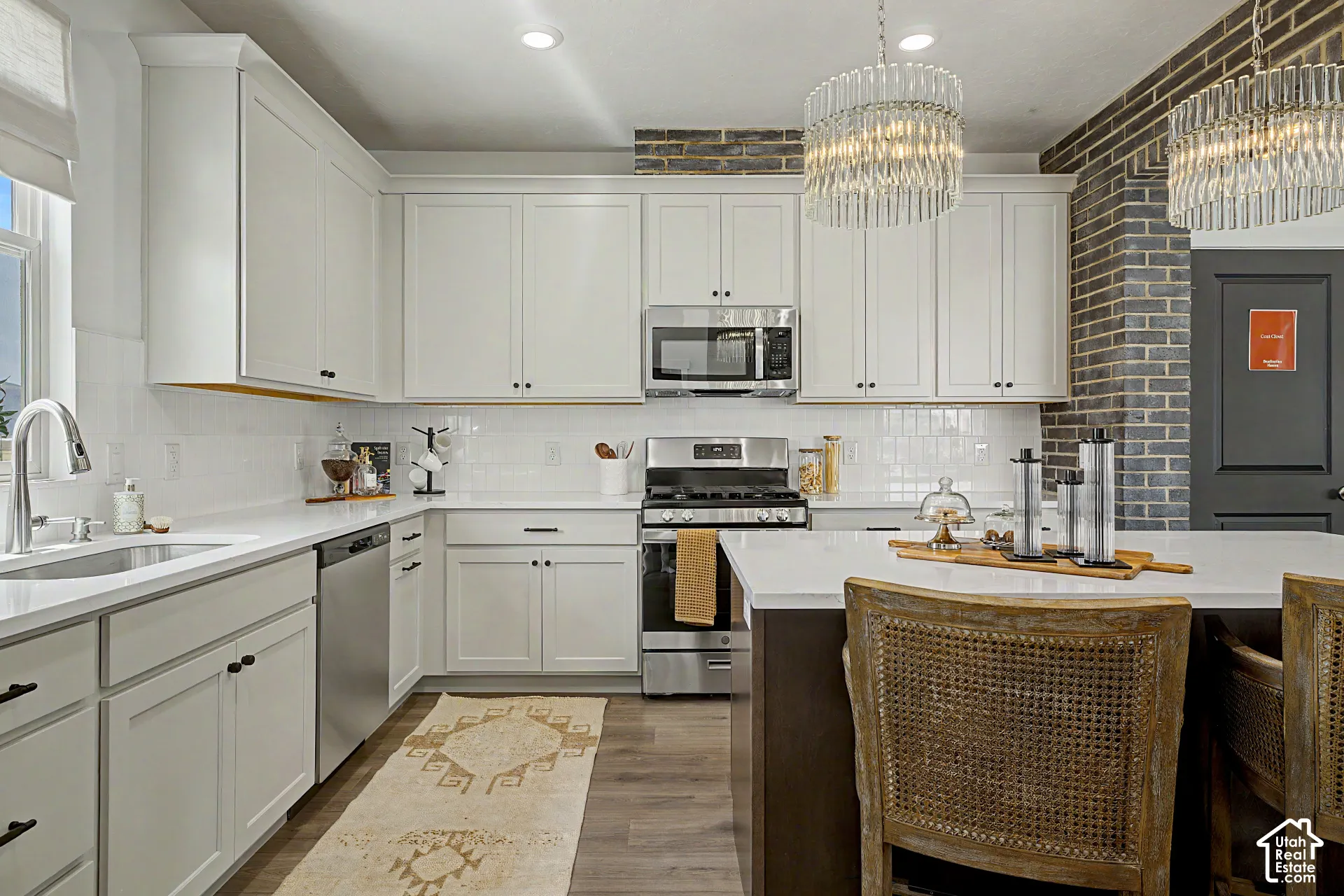 Modern kitchen featuring white shaker cabinetry, stainless steel appliances, white subway tile backsplash, and wood-finish flooring