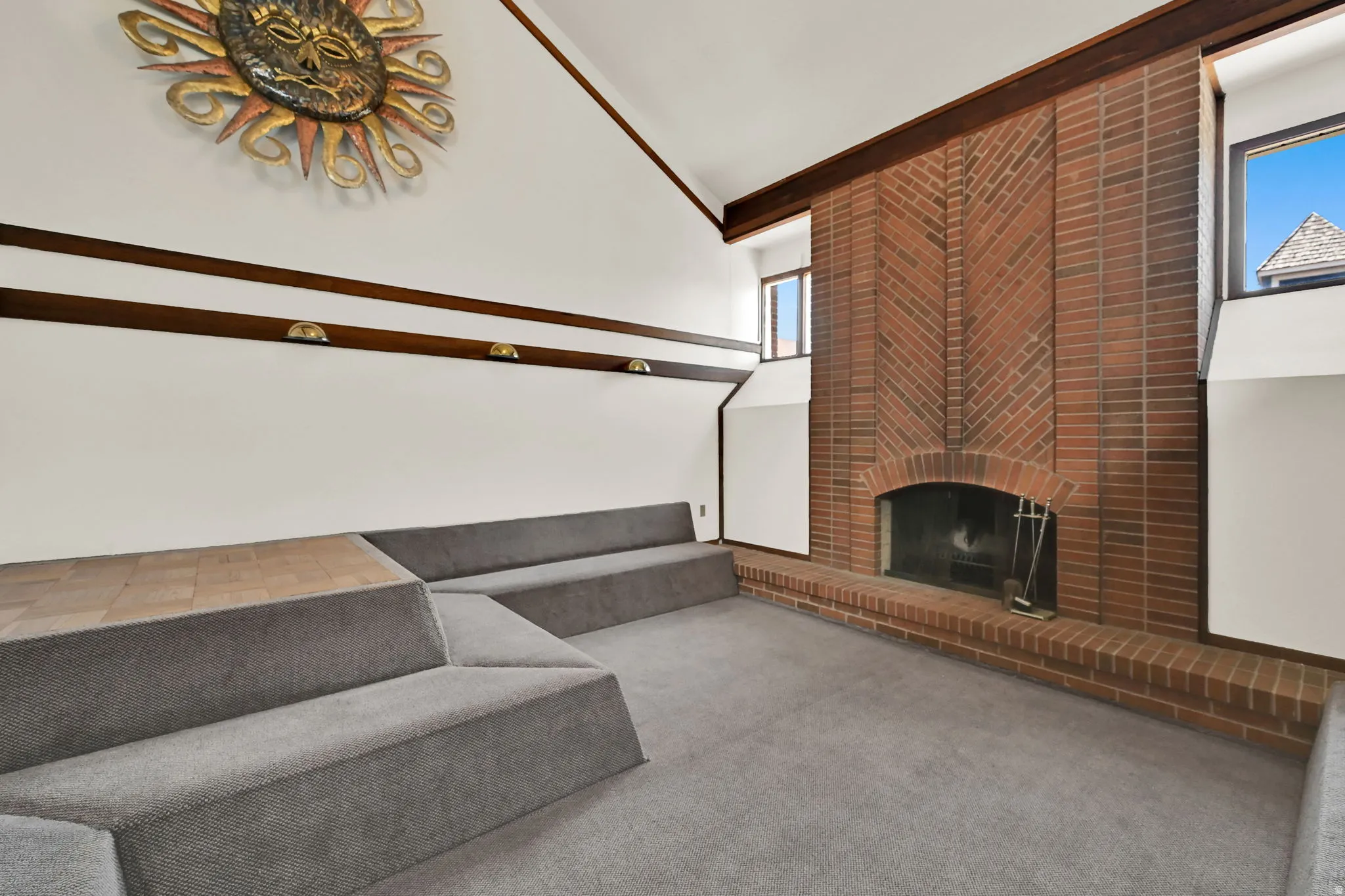 Spacious room featuring a brick fireplace with an arched opening, high vaulted ceilings, and upper transom windows