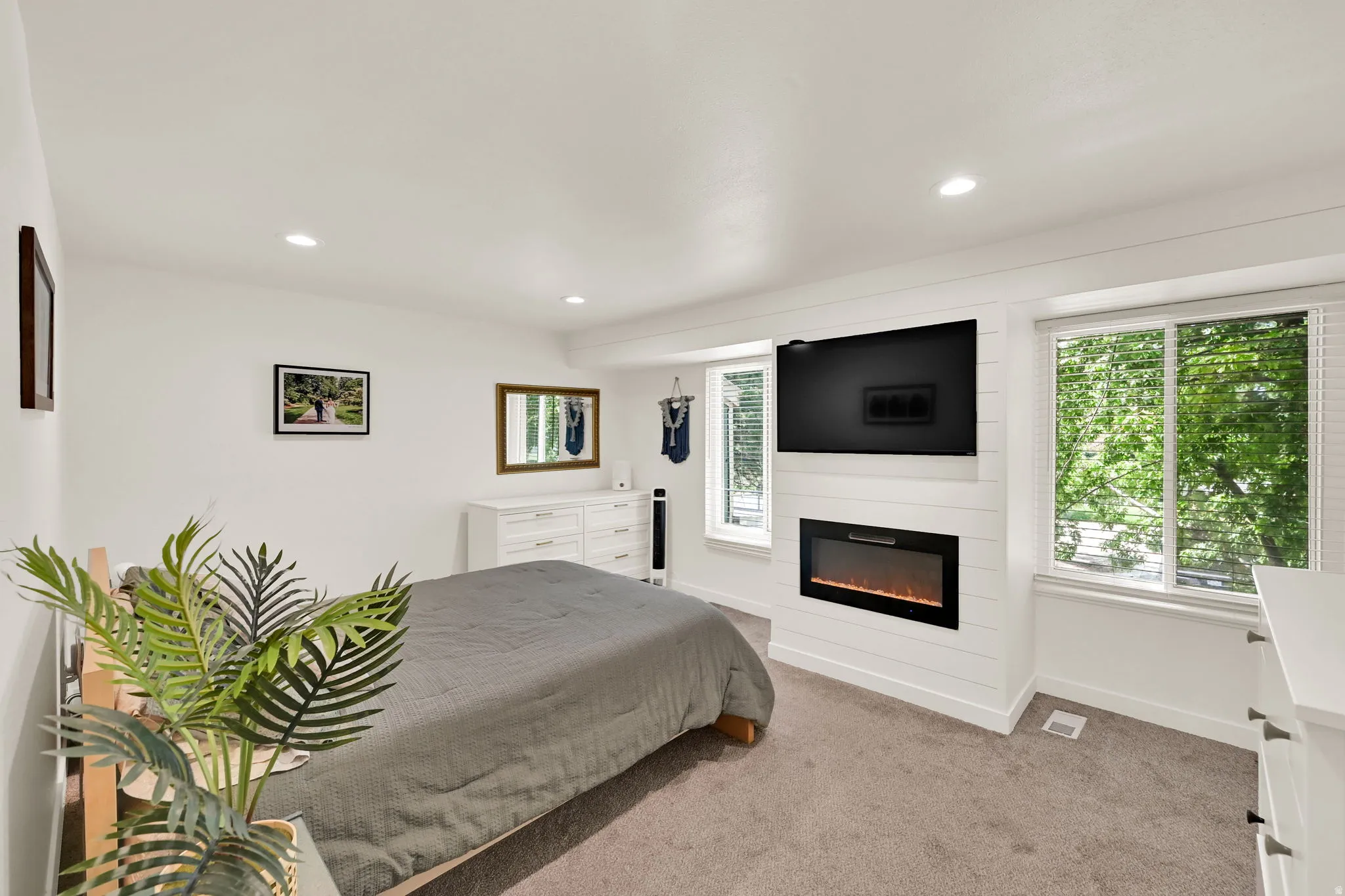 Recessed lighting, soft carpet flooring, electric fireplace with a shiplap surround, and multiple windows