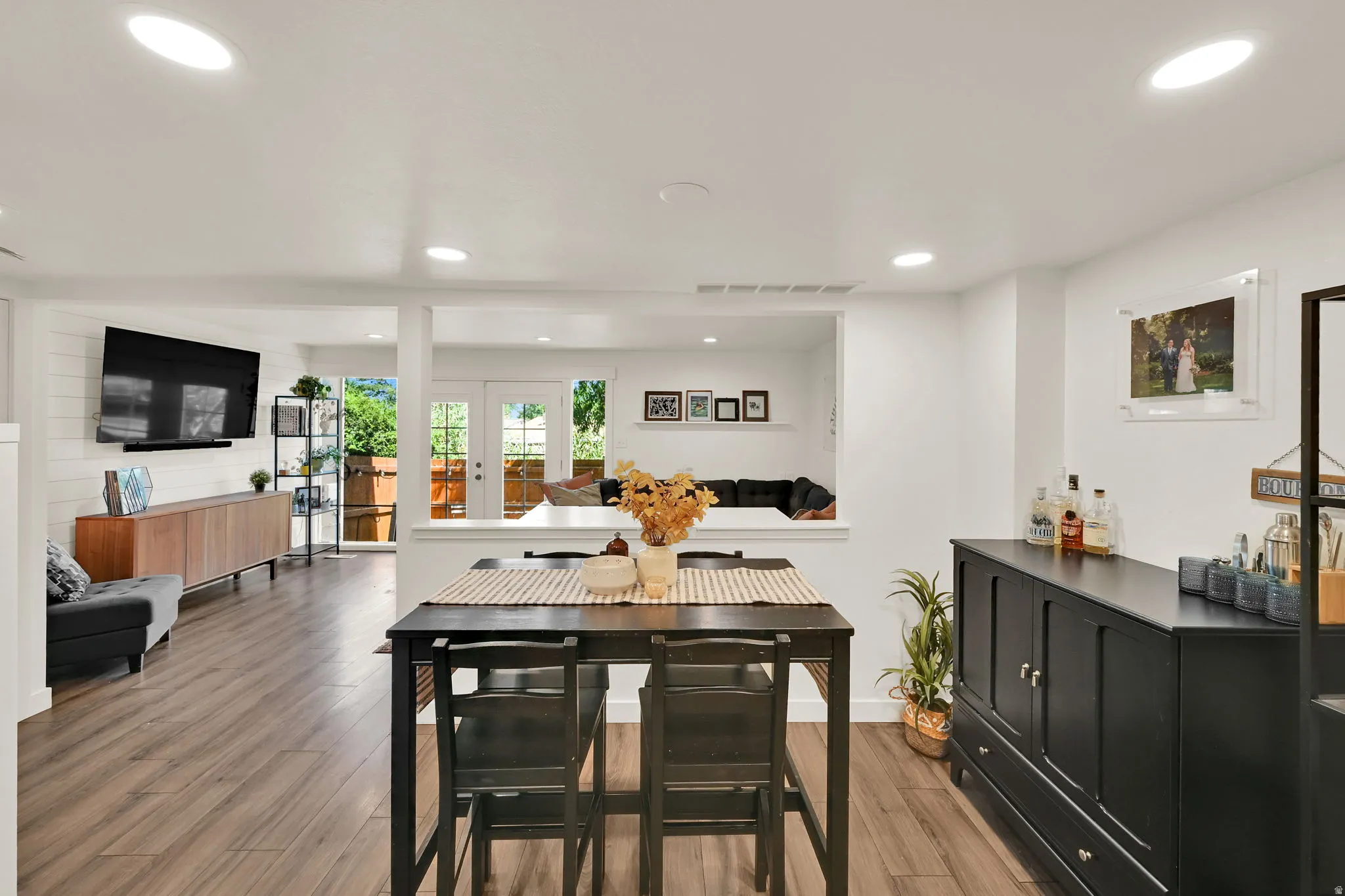 Recessed lighting, wood-finish flooring, white shiplap accent wall, white French doors, and a built-in credenza