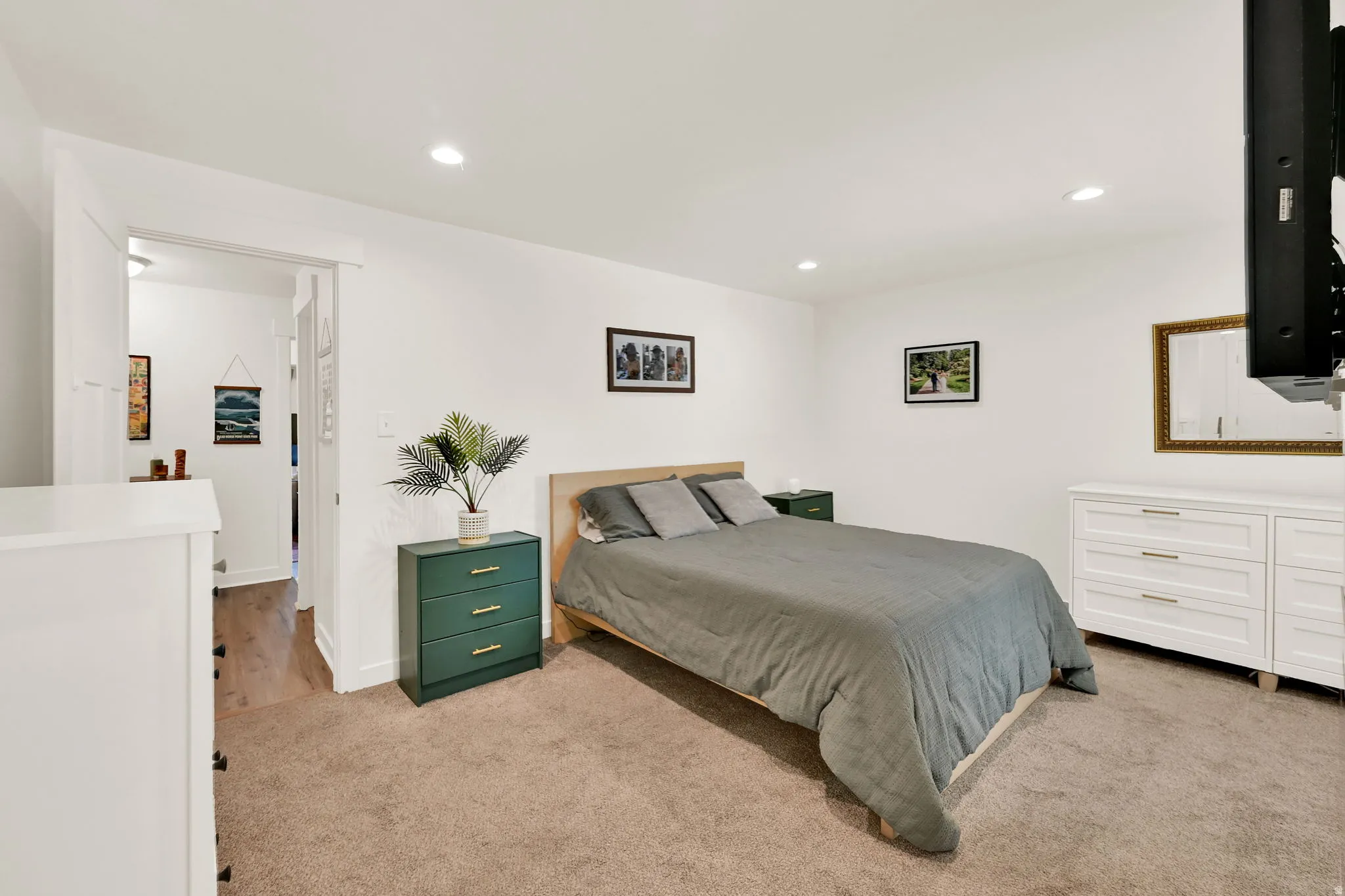 Recessed lighting illuminates the carpeted flooring and white walls
