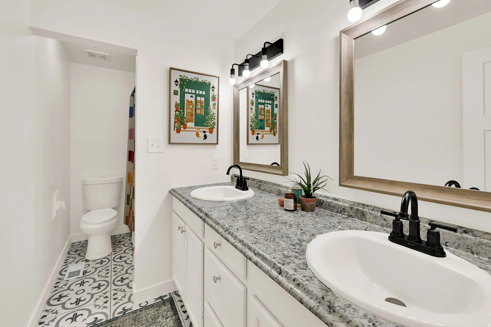 Double vanity with integrated sinks, granite-look countertop, and matte black fixtures on upper level with the bedrooms