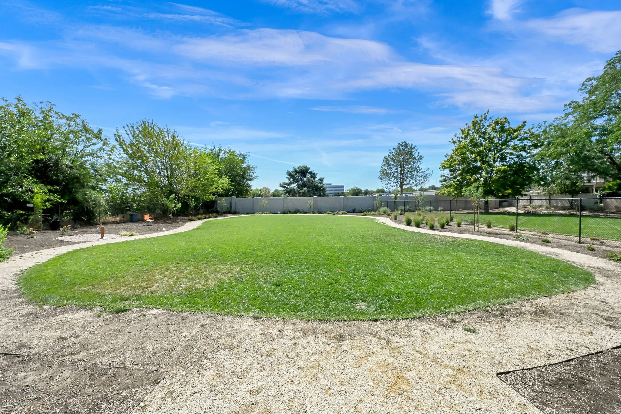 Expansive grassy area with a curvilinear gravel pathway and perimeter landscaping