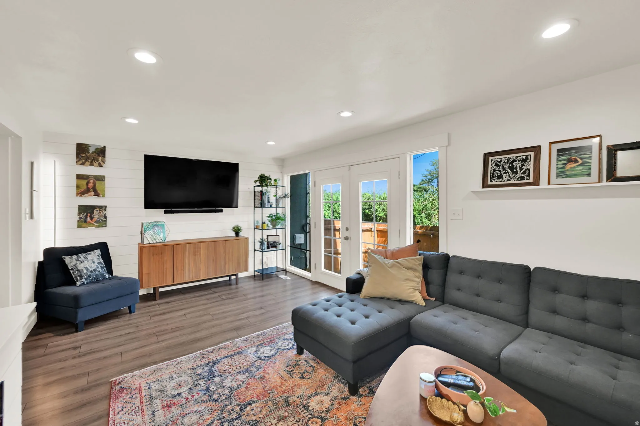 Recessed lighting, wood-finish flooring, white shiplap accent wall, and double French doors to the outdoor area