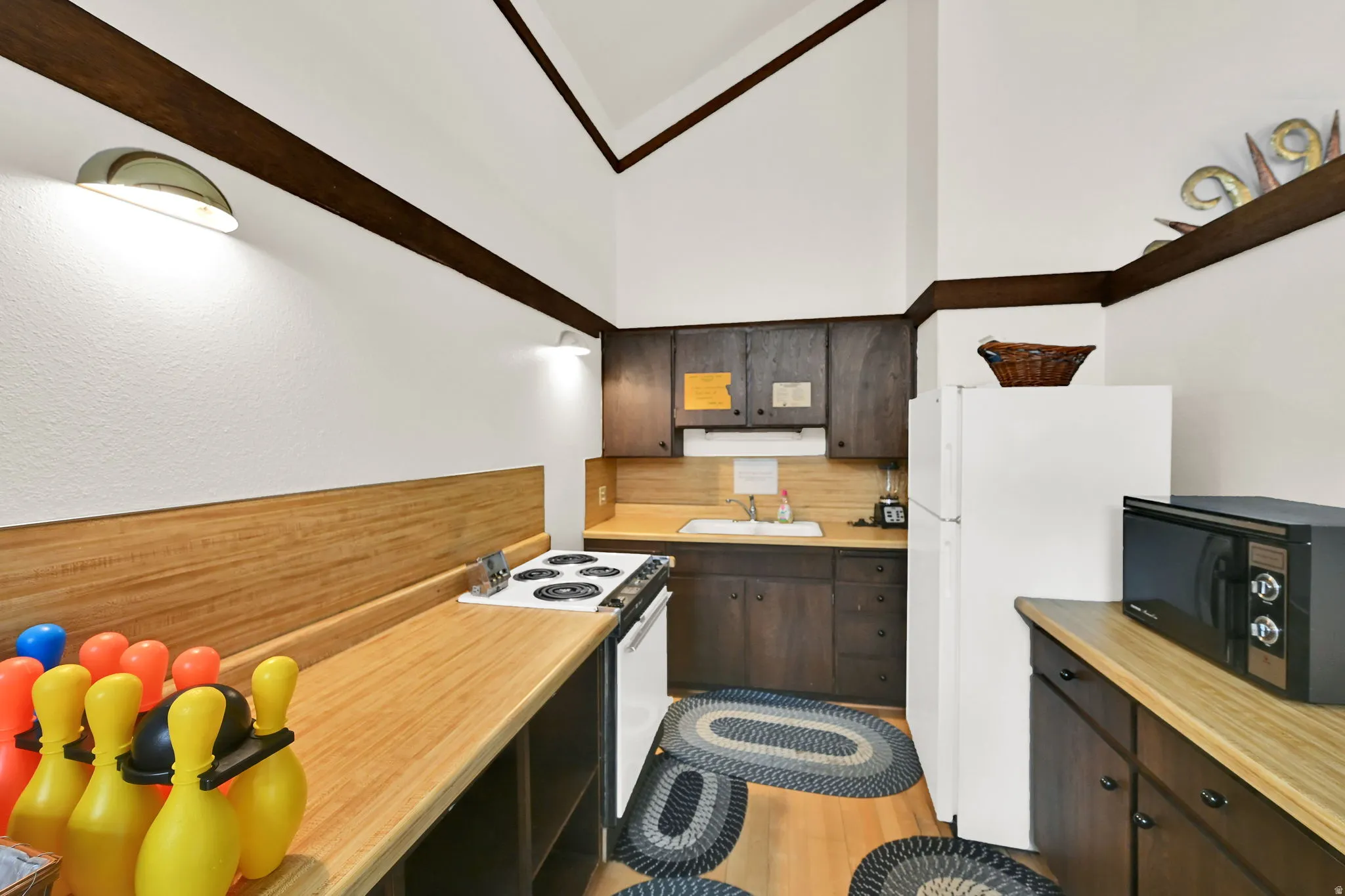 Kitchen featuring wood-finish countertops, dark wood-finish cabinetry, a freestanding range, and a refrigerator