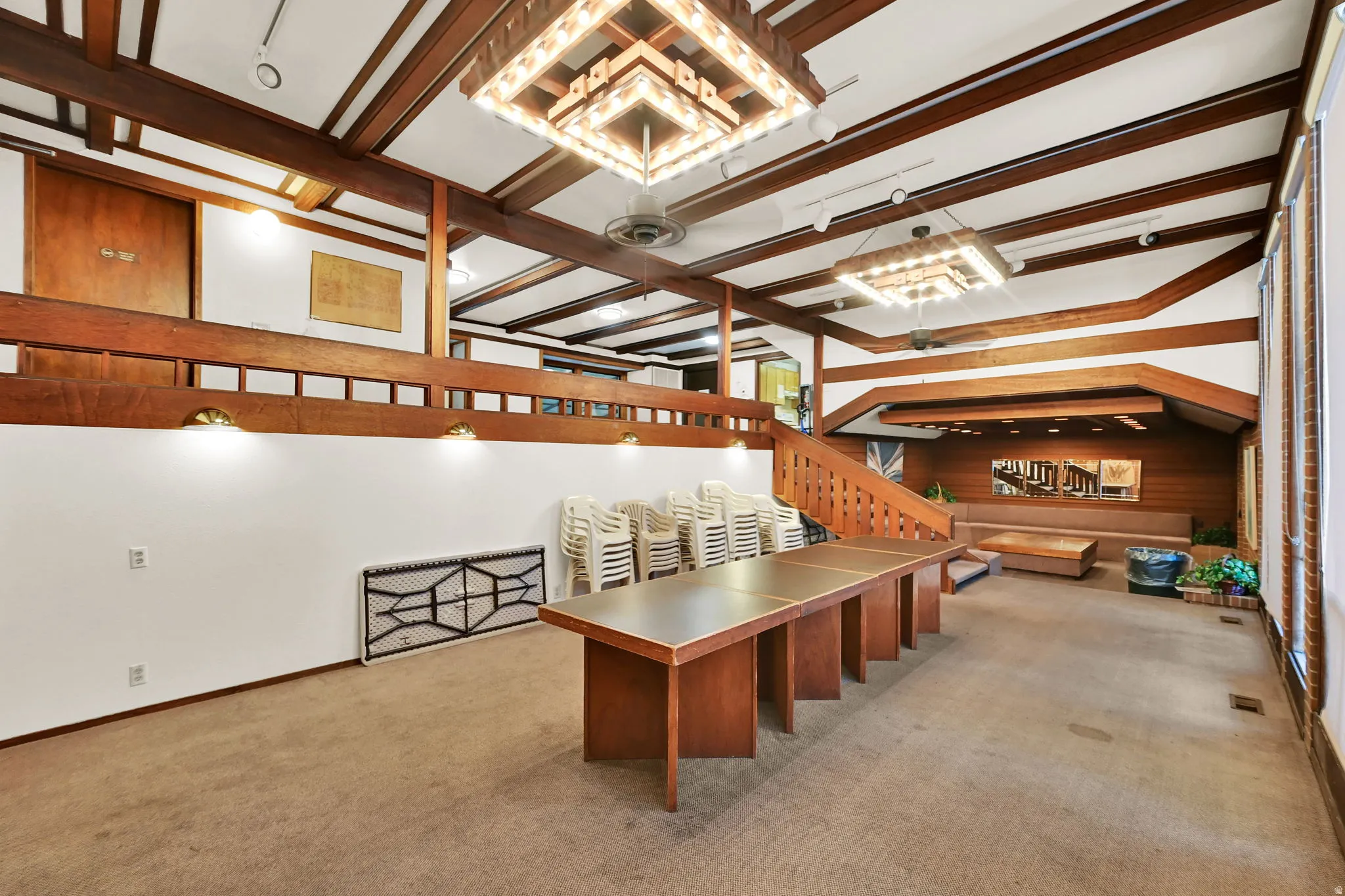 Exposed wood beams, multi-level design, built-in bench seating, multiple windows, and decorative lighting fixtures