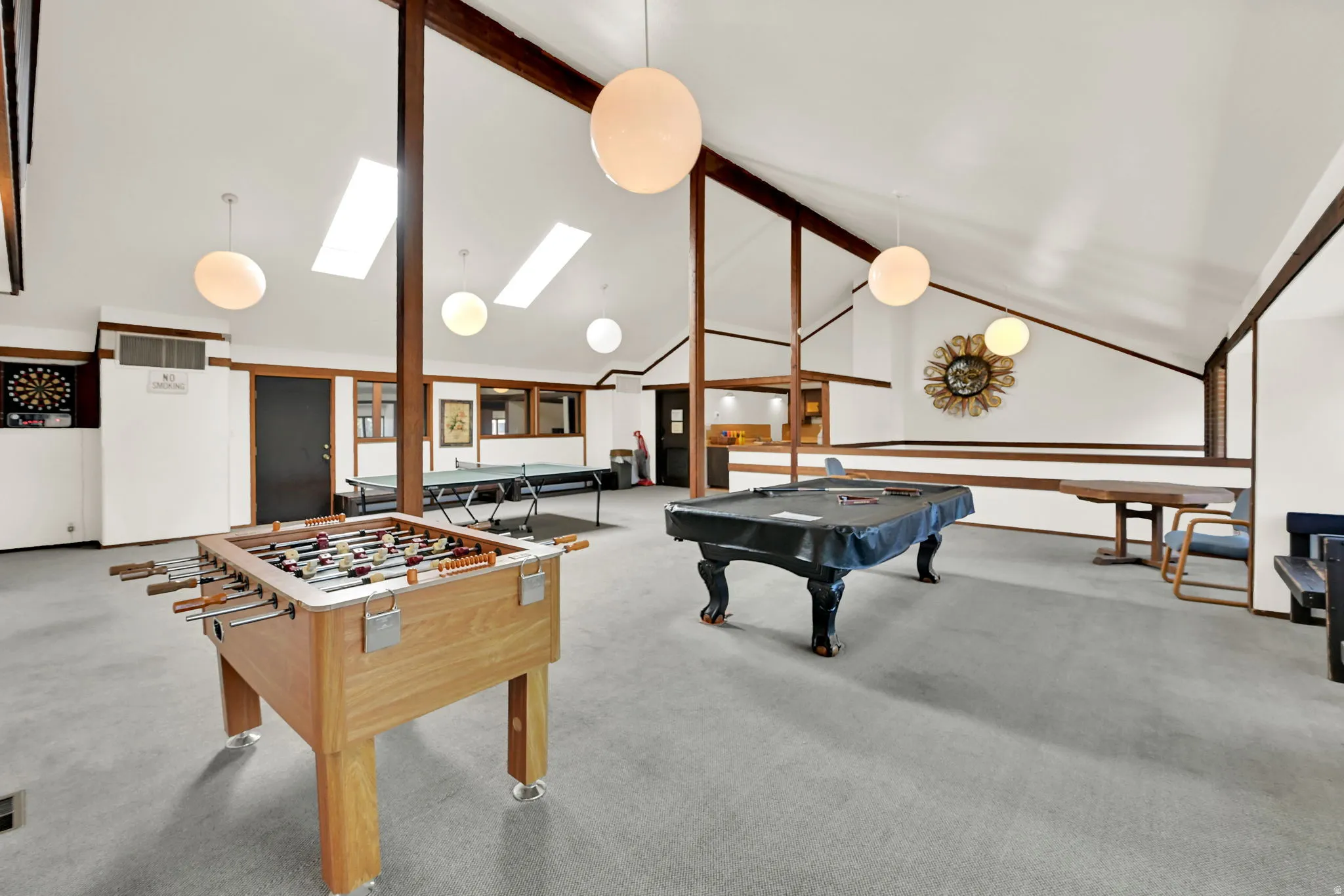 Vaulted ceilings with exposed wood beams, multiple skylights, and spherical pendant lighting