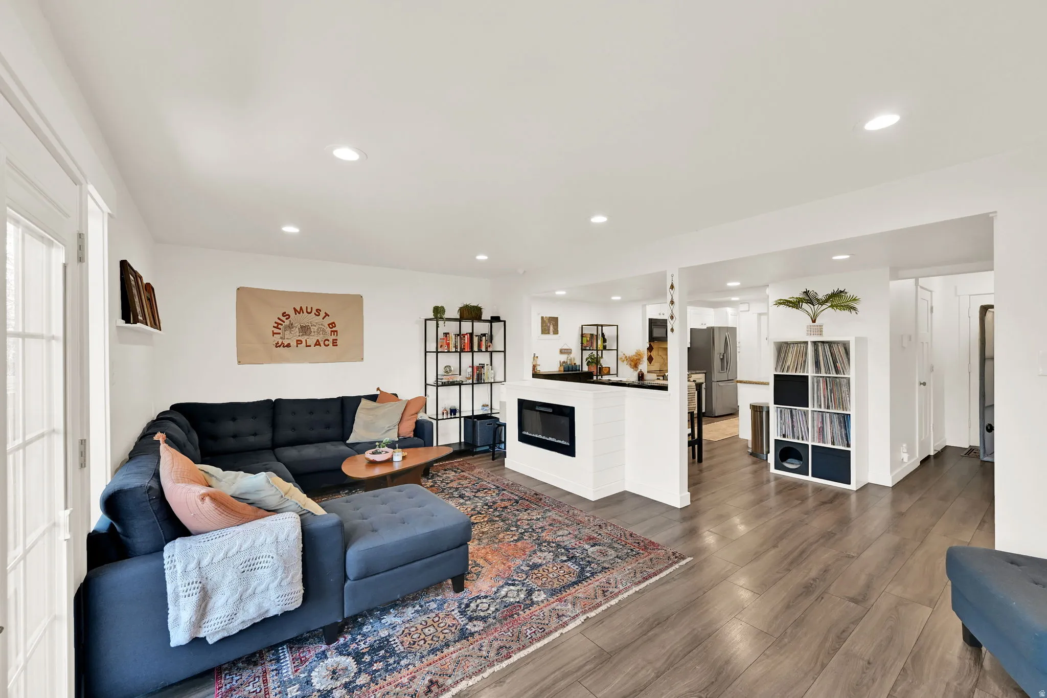Recessed lighting, wood-finish flooring, white walls, built-in fireplace, and French doors