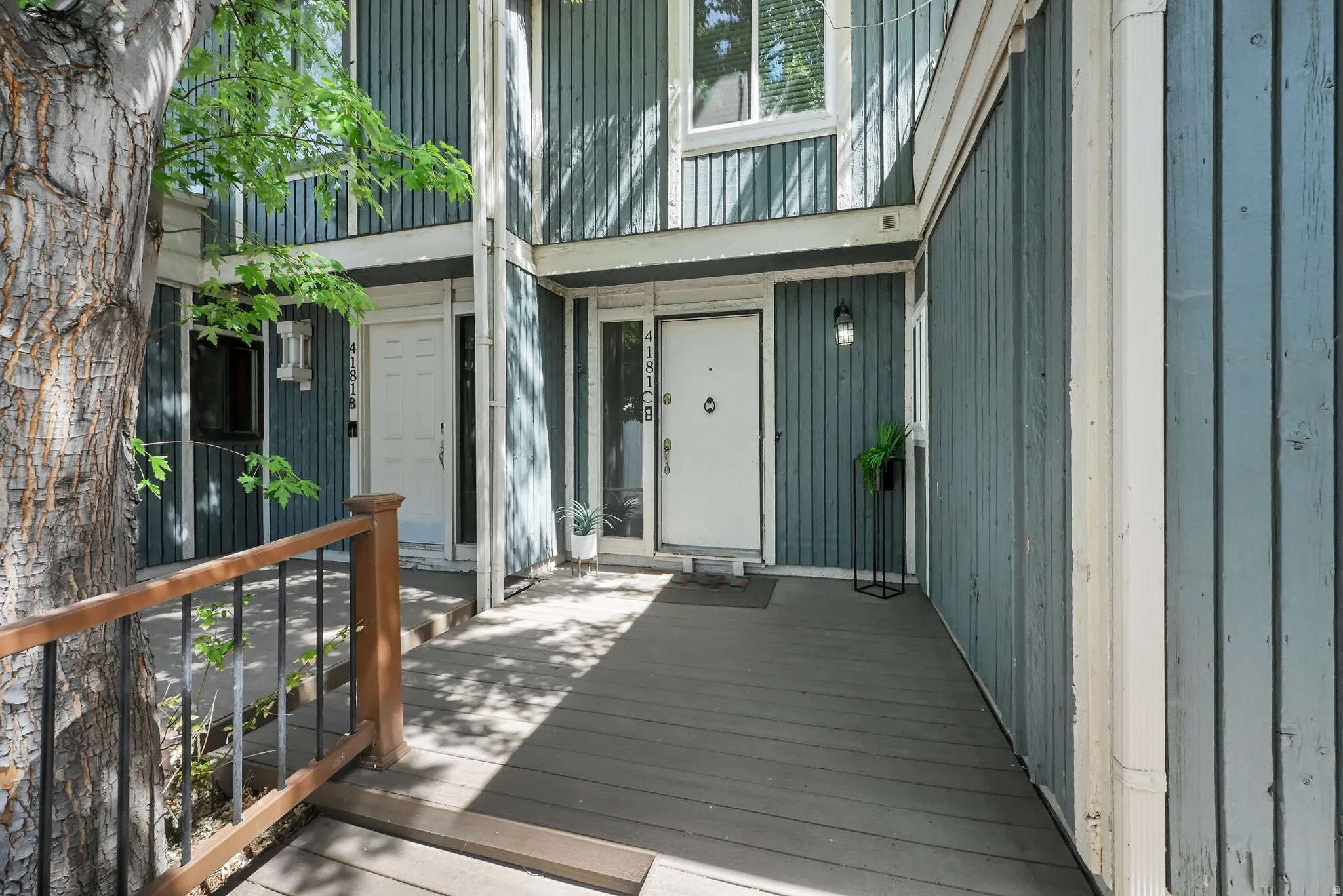 Entryway with wood-look siding, white entry door, and exterior lighting fixture