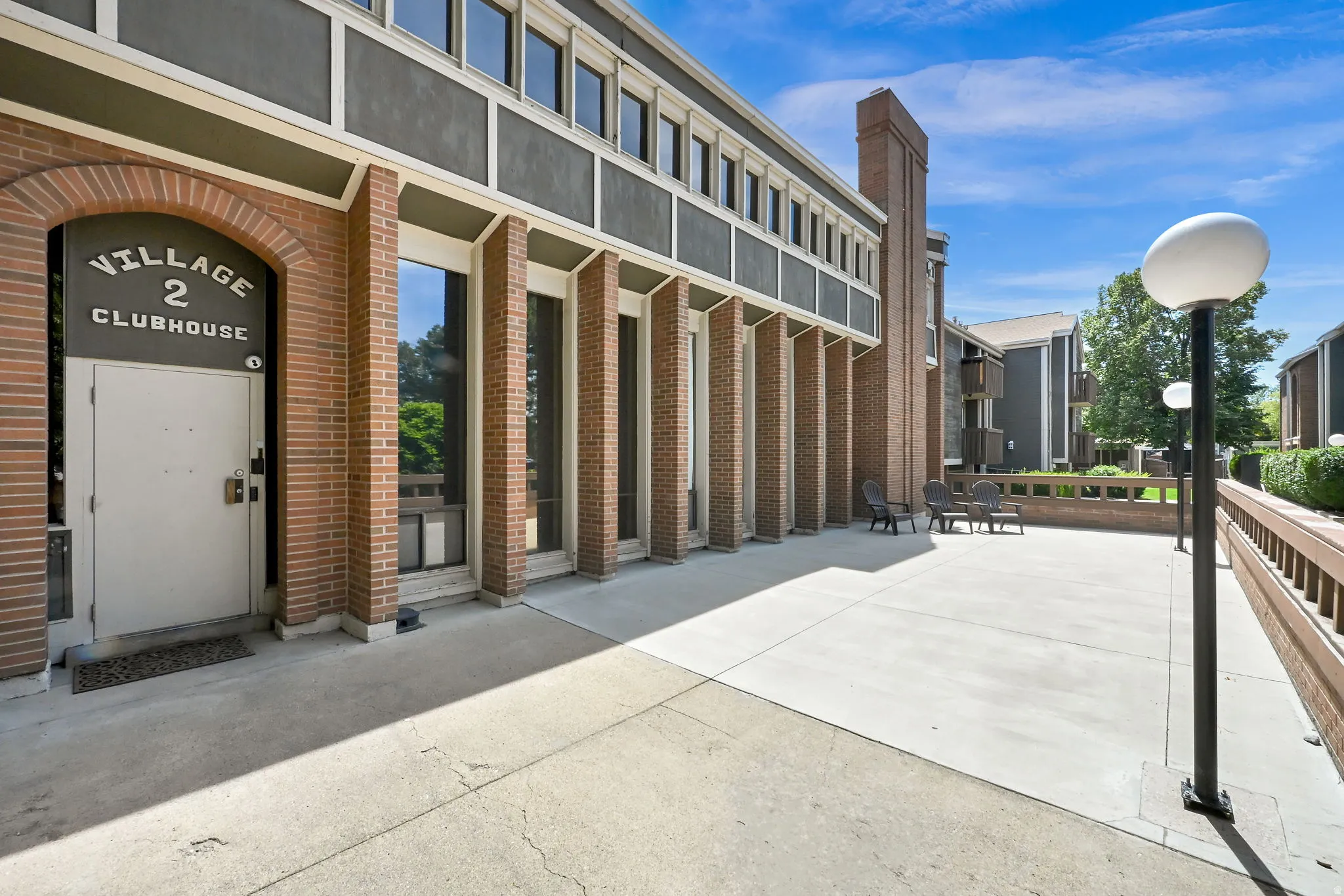 Brick facade with arched entryway, large windows, and an expansive concrete patio