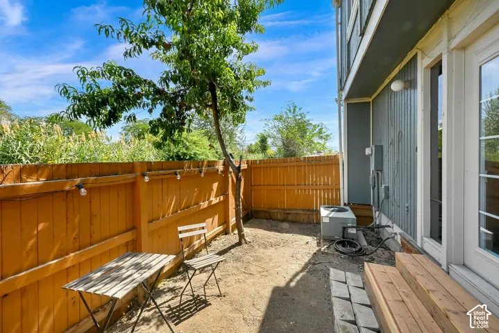 Fenced outdoor space featuring a mature tree, wood plank siding, and a multi-pane glass door