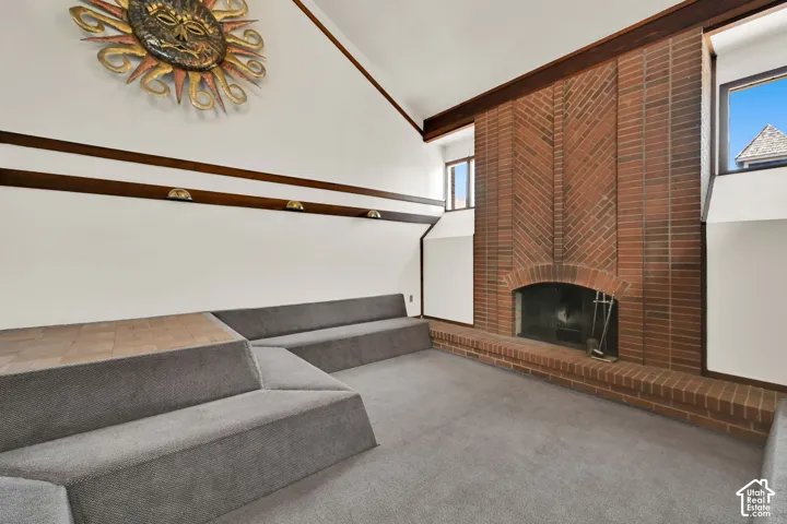 Spacious room featuring a brick fireplace with an arched opening, high vaulted ceilings, and upper transom windows