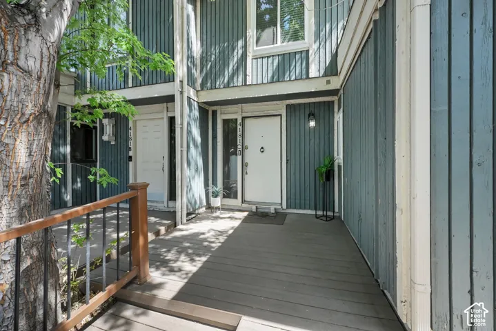 Entryway with wood-look siding, white entry door, and exterior lighting fixture