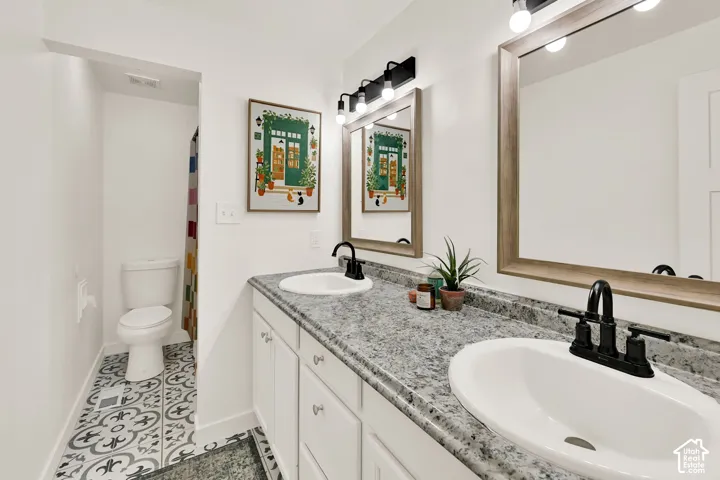 Double vanity with integrated sinks, granite-look countertop, and matte black fixtures on upper level with the bedrooms