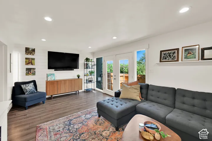 Recessed lighting, wood-finish flooring, white shiplap accent wall, and double French doors to the outdoor area