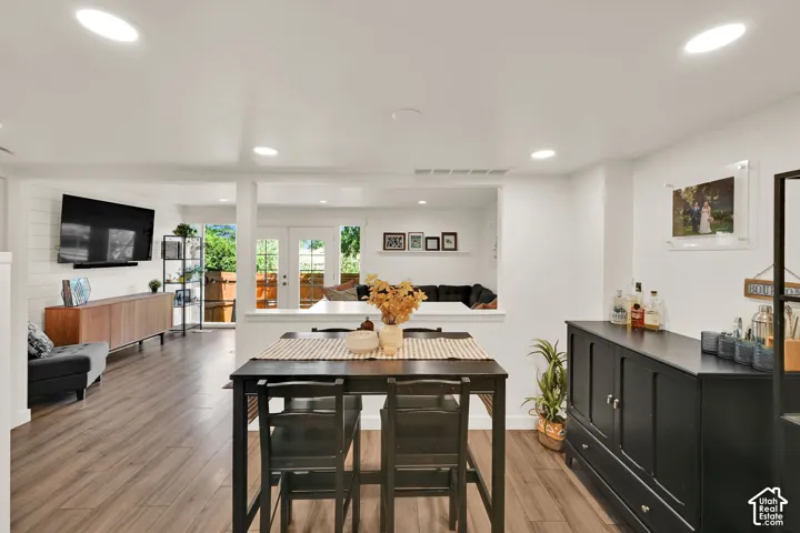 Recessed lighting, wood-finish flooring, white shiplap accent wall, white French doors, and a built-in credenza