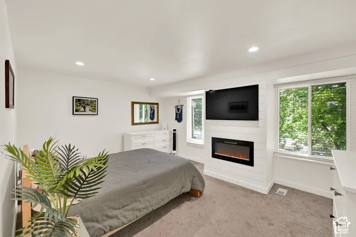 Recessed lighting, soft carpet flooring, electric fireplace with a shiplap surround, and multiple windows