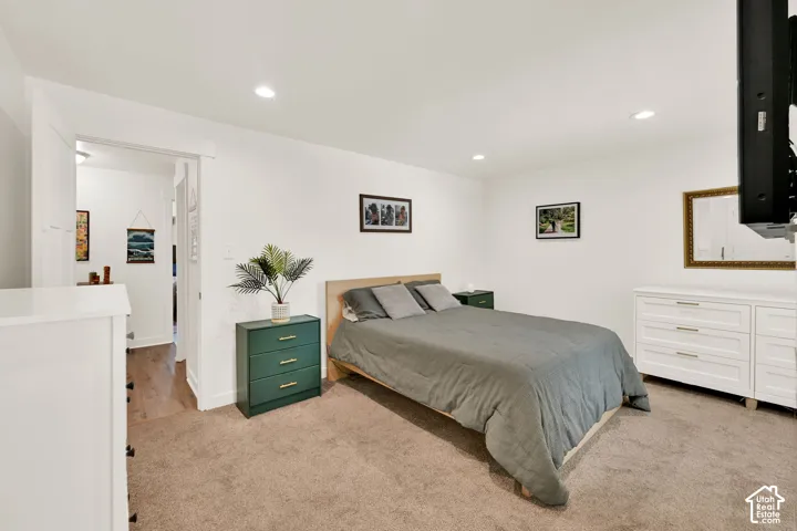 Recessed lighting illuminates the carpeted flooring and white walls