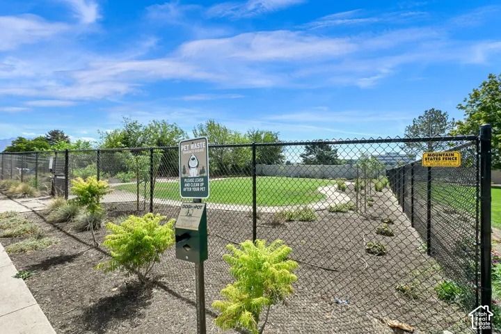 Dog park with a pet waste station, bordered by landscaped ground cover and mature trees