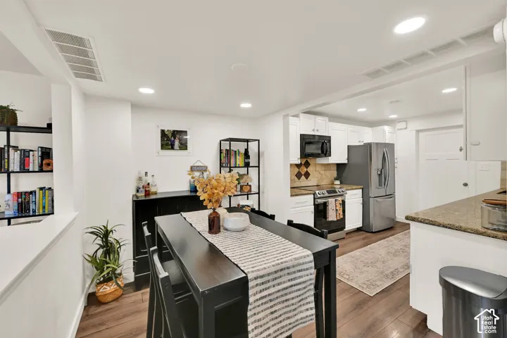 Open-concept kitchen and dining area featuring recessed lighting, wood-finish flooring, and white cabinetry