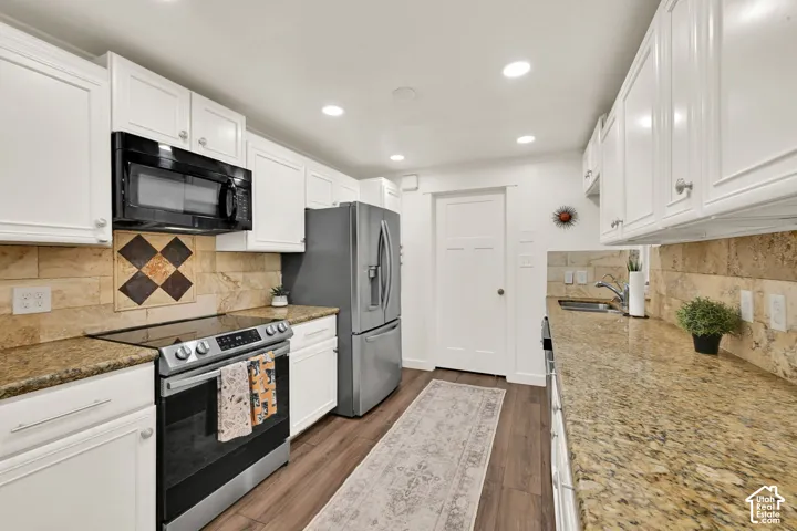 Granite countertops, white shaker cabinetry, stainless steel appliances, tile backsplash, and wood-finish flooring