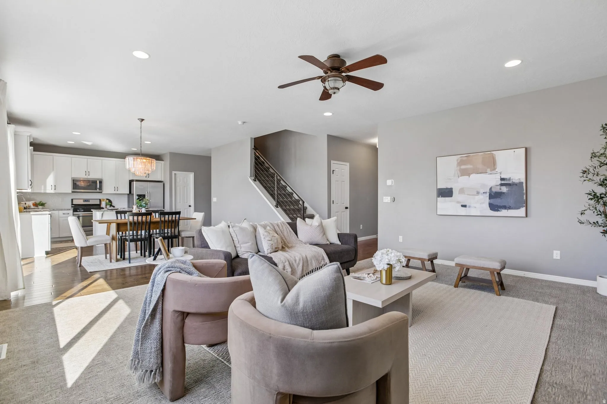 Open-concept living space with recessed lighting, wood-finish flooring, and a modern staircase with metal railings