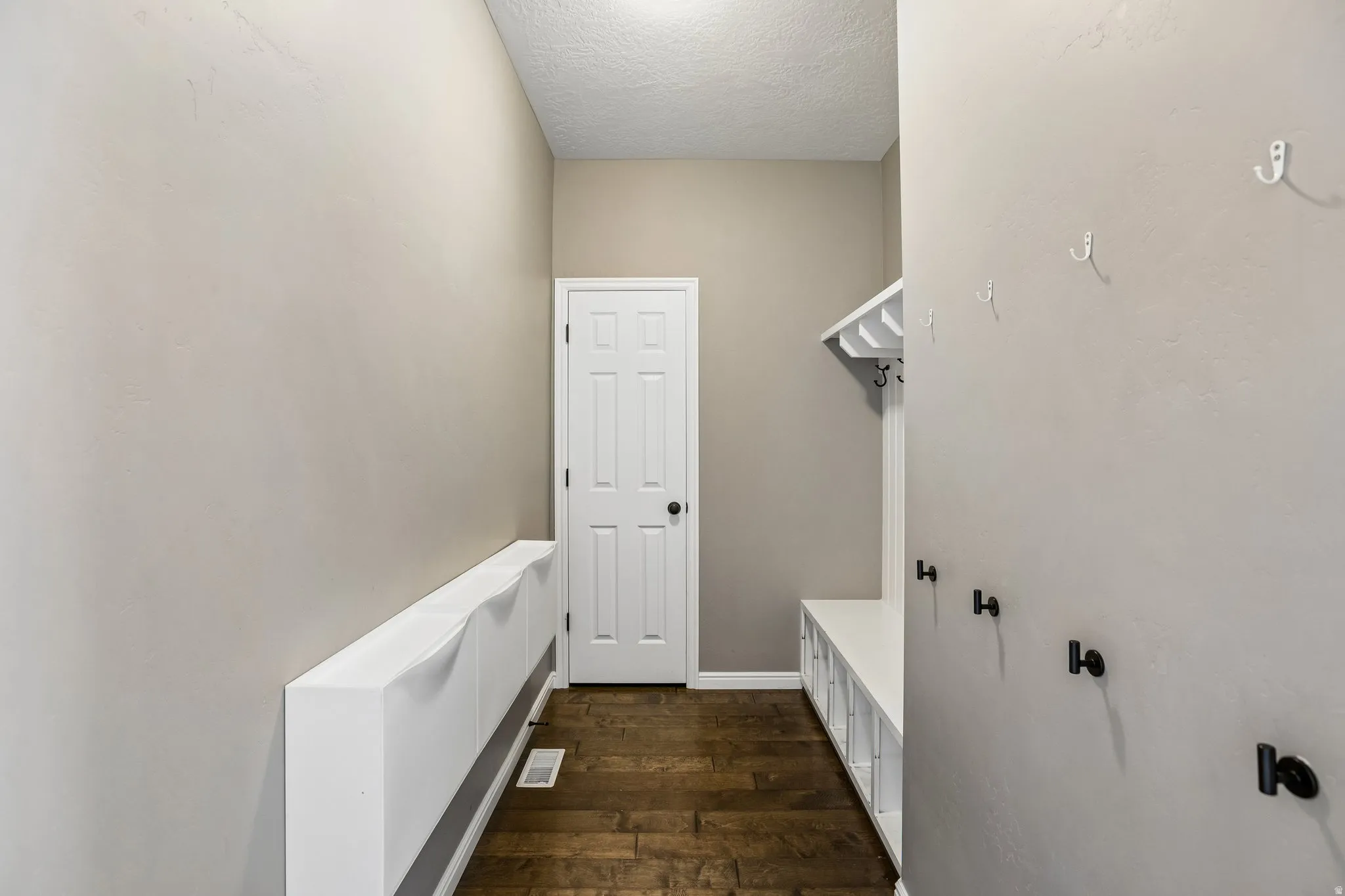 Built-in storage bench with cubbies, wood-finish flooring, and a paneled door