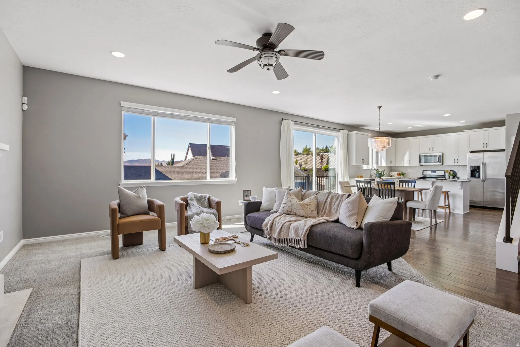 Open-concept living area featuring a ceiling fan, recessed lighting, and large windows