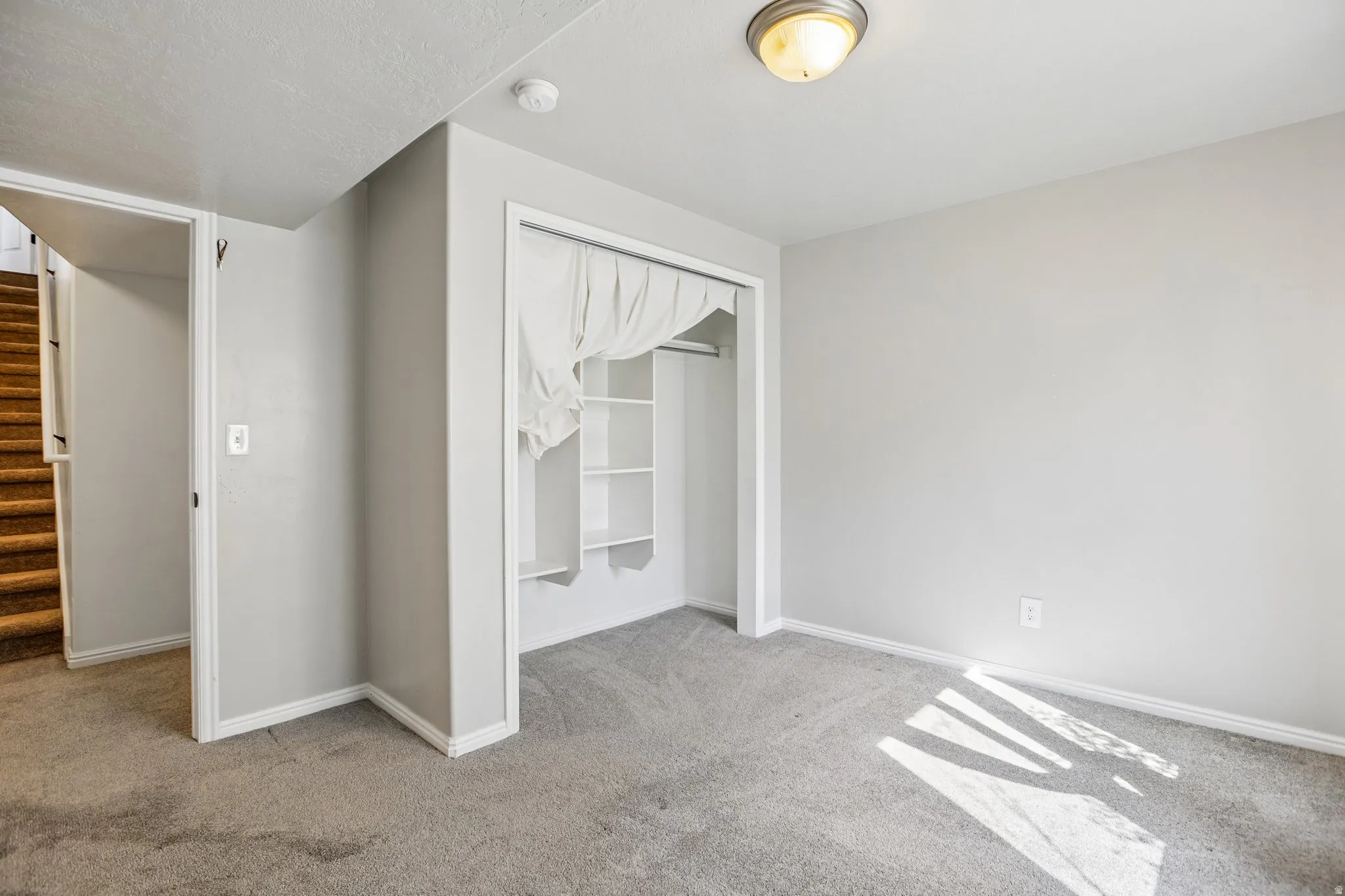 Carpeted flooring, built-in open shelving, surface-mounted ceiling light fixture, neutral wall color, and white trim